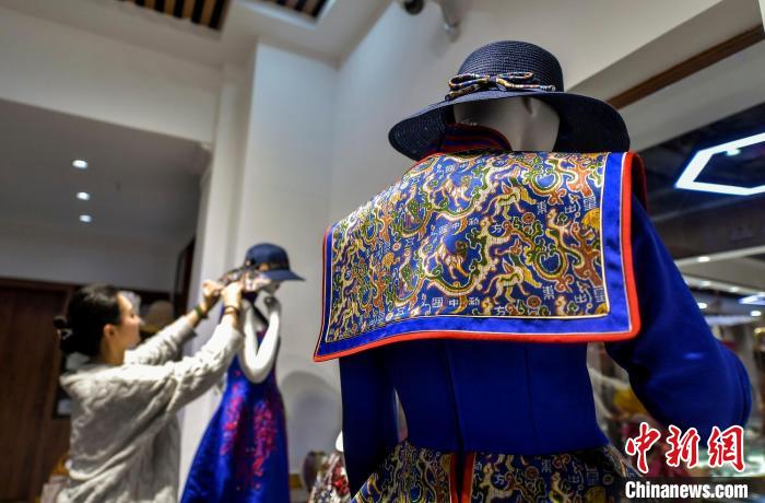 工作人员正在整理融入“五星出东方利中国”织锦护膊图案的服饰。中新网记者 刘新 摄